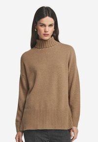 Brauner Rollkragenpullover aus weichem Strickstoff, mit geripptem Muster an den Bündchen und dem Saum, in lockerer, entspannter Passform.