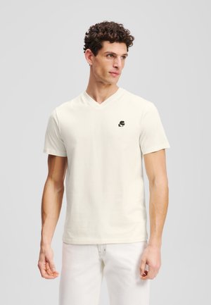 Lys creme V-hals t-shirt med kortærmer i bomuld, prydet med et lille sort logo på brystet, glat tekstur og almindelig pasform.