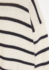 Tissu tricoté couleur crème avec des rayures noires horizontales uniformément espacées et une couture visible dans la partie supérieure.