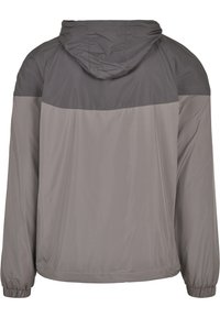 Tvåfärgad grå jacka med huva och elastiska muddar, visad från baksidan.