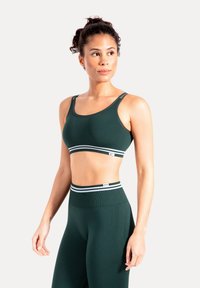Ciemnozielony sportowy biustonosz z grubą białą paskowaną opaską, wykonany z gładkiej tkaniny, z szerokimi ramiączkami i dopasowanym krojem.
