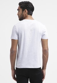Grijze T-shirt met korte mouwen in een lichtgewicht stof, met een rechte zoom en een zachte textuur, gedragen met zwarte broeken.