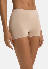 Boxer briefs beige sin costuras con una textura suave, cinturilla elástica y longitud de pierna corta, diseñados para la comodidad y mínima visibilidad.