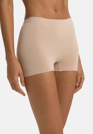 Beige saumattomat boxerit, joissa on sileä rakenne, joustava vyötärö ja lyhyt lahkeen pituus, suunniteltu mukavuutta ja minimaalista näkyvyyttä varten.