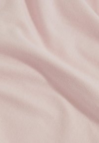 Tissu en coton rose clair avec une texture douce, présentant une surface lisse, légèrement extensible et une brillance subtile.