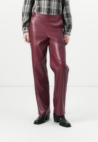 Bordeaux faux leren broek met een rechte snit, voorzien van een gladde textuur, zijnaad en zwarte knoopaccenten in de taille.