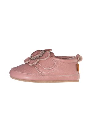 Mäkká ružová detská topánka s semišovou podrážkou a veľkou viacvrstvovou kvetinovou dekoráciou na vrchu, bočný pohľad na bielom pozadí.