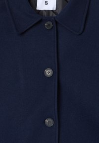 Cappotto di lana blu navy con colletto classico, dotato di due bottoni neri e un design semplice. L'etichetta mostra la taglia "S" all'interno del colletto.