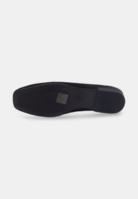 Semelle de chaussure noire avec une traction texturée, forme légèrement courbée et bord lisse. Présente une légère impression de logo et une finition en matériau durable.