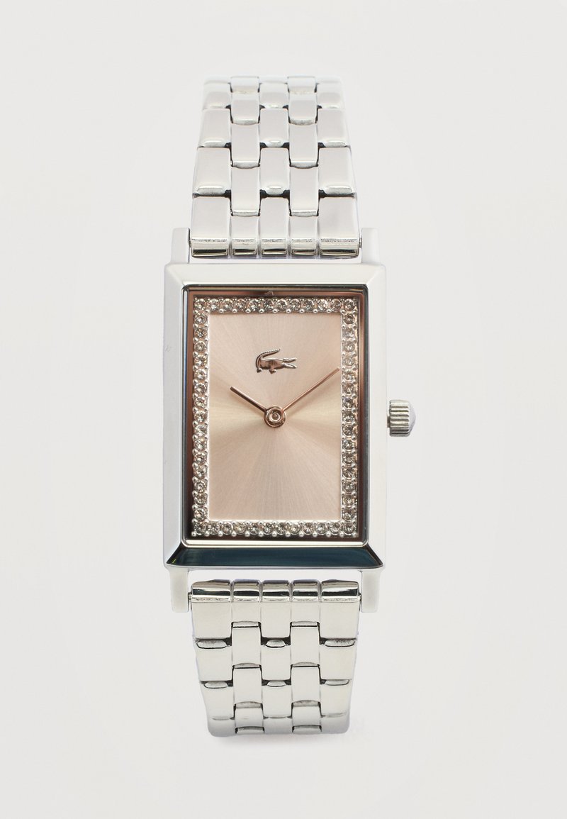 Montre-bracelet rectangulaire en argent avec bracelet métallique à maillons, cadran en or rose, bordure en cristal, deux aiguilles fines et un petit logo de crocodile à midi.