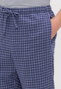 Calças de lounge xadrez azul marinho feitas de um tecido leve, com uma cintura elástica com cordão, bolsos laterais e um padrão de grelha.