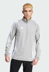 Grijs sportief half-zip bovenstuk met lange mouwen, witte strepen op de schouders en een "AEROREADY" label onderaan. Voorzien van een opstaande kraag.