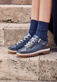 Navy leather sneakers featuring a textured surface, lace-up design, and side zipper. Details include light blue laces and brown accents.