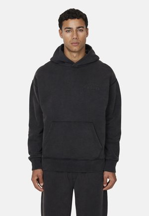 Hoodie en coton noir avec une poche avant, des poignets et un ourlet côtelés. Présente un logo embossé sur la poitrine et une capuche spacieuse.