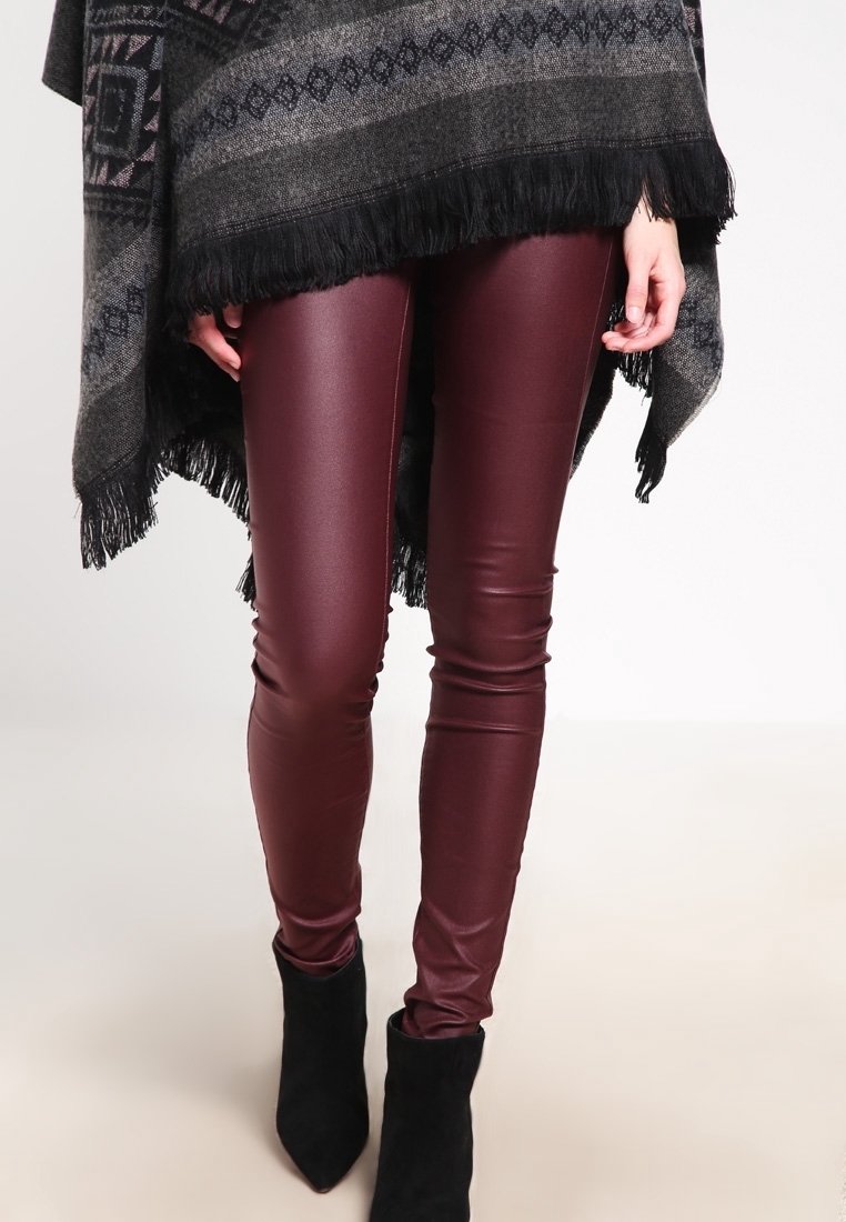 Burgundské legíny z umělé kůže s lesklým povrchem, přiléhavý střih a kombinované s černými kotníkovými botami na podpatku.