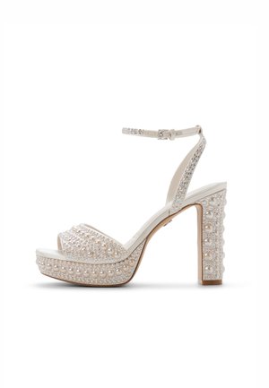 White high-heeled sandal with platform, featuring pearl and rhinestone embellishments, adjustable ankle strap, and textured block heel.