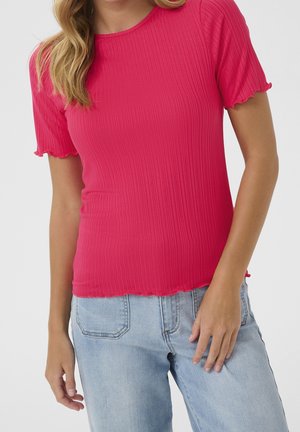 Rosa, geripptes Kurzarmshirt mit rundem Ausschnitt und gezackten Kanten, kombiniert mit hellblauen Jeans.