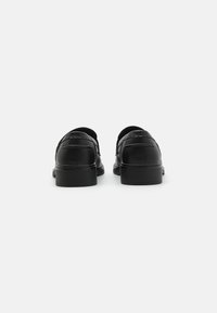 Black leather shoes with a smooth texture, rounded back, and low, solid heel. Decorative stitching on the sides adds detail.