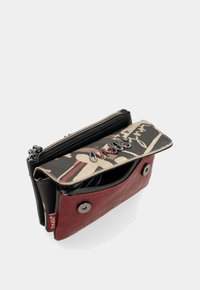 Portafoglio multicolore con zip, caratterizzato da una base in pelle rossa, una patta decorata con disegni astratti e accenti argento sulla parte superiore.
