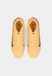 Een paar gele sportschoenen met blauwe swoosh-logo's, veters gestrikt, vanbovenaf gezien op een witte achtergrond.