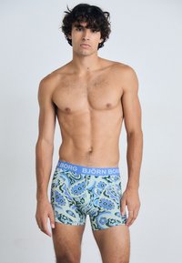 Boxershorts med blått elastiskt midjeband, med ett färgglatt virvlande mönster i nyanser av grönt, blått och lila.