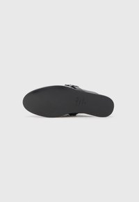 Pantof black din piele cu o textură netedă, vârf rotunjit și talpă plată neagră. Are un accent cu cataramă pe lateral.