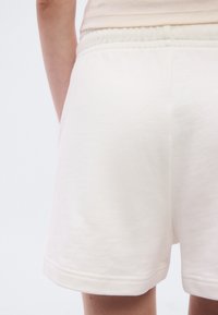 Ανοιχτό μπεζ βαμβακερά σορτς με απαλή υφή, ελαστική μέση και πλαϊνές τσέπες. Το τελείωμα φτάνει πάνω από το γόνατο.