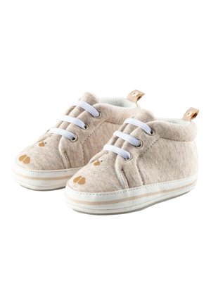 Beige bløde baby sko med hvide snørebånd og et ande-design foran, med en trække strop bagpå og en hvid sål.