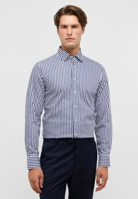 Marineblau-weiß gestreiftes Langarmhemd mit Button-Down-Kragen, taillierte Passform, glatte Textur, kombiniert mit dunkler Hose.
