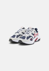 Vita och marinblå sportskor med röda detaljer. Har överdel i mesh och mocka, dämpad sula och snörning.