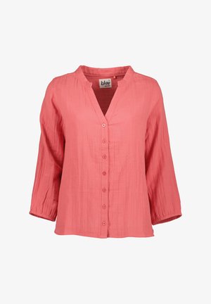 Blouse longue à manches longues couleur corail avec boutons sur le devant et petit col montant, en tissu léger texturé.