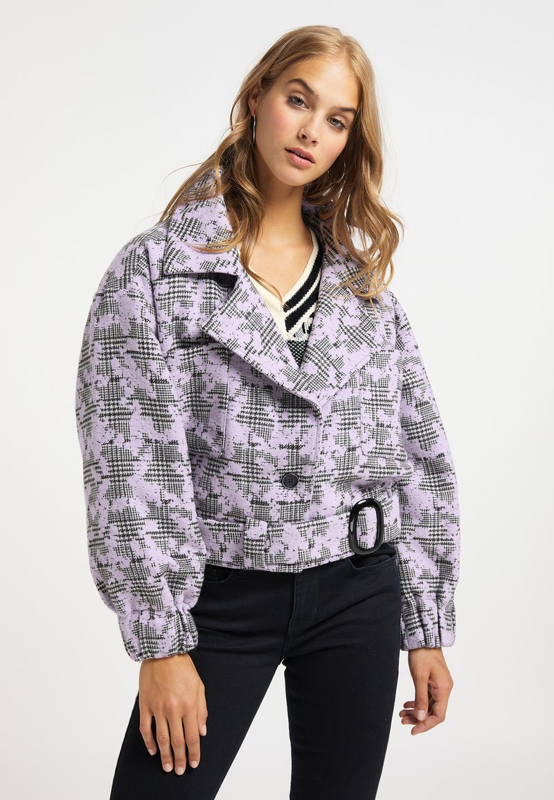 Lilla ternet cropped jakke med dobbeltbrystet design, stor krave og ballonsleeves, med sorte knapper og bælte detaljer.
