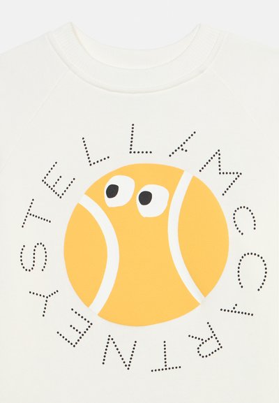 Λευκό ρούχο με παιχνιδιάρικο κίτρινο γραφικό τεννιστικής μπάλας με καρτούν μάτια, περιβαλλόμενο από κειμενικό μοτίβο με κουκκίδες "TENNIS THELLA MCC" σε κυκλικό σχήμα.