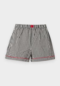 Boxer pour hommes à carreaux noirs et blancs avec ceinture élastique, détails de surpiqûres rouges près de l'ourlet et étiquette de marque rouge au centre devant.