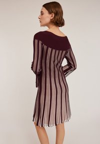 Polvimittainen burgundiväri mekko, jossa on pystysuorat raidat. Ominaisuuksiin kuuluvat pitkät hihat, pyöreä pääntie ja lievästi levenevä helma. Kevyt neulekudosmateriaali.