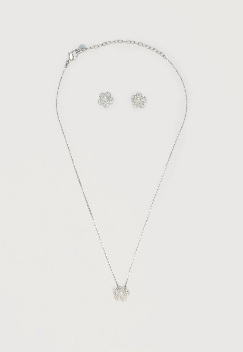 Ensemble de collier en argent et boucles d'oreilles assorties avec pendentifs en forme de fleur, ornés de perles centrales et de petits cristaux environnants.