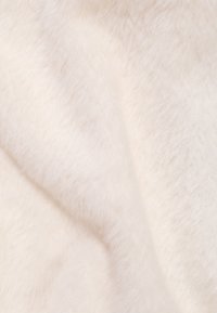 Weiches, cremefarbenes Kunstfell mit einer flauschigen Textur und sanften Falten.