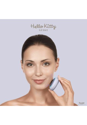 Kvinde bruger en rund hudplejeenhed med blåt lys på kinden, neutral baggrund, teksten "Hello Kitty GESKE" ovenover.