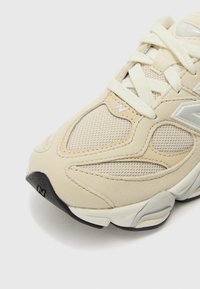 Adi Scarpe sport beige cu detalii din plasă și nubuc, accente texturate, șireturi plate, vârf rotund și talpă din cauciuc negru. Logo pe lateral.