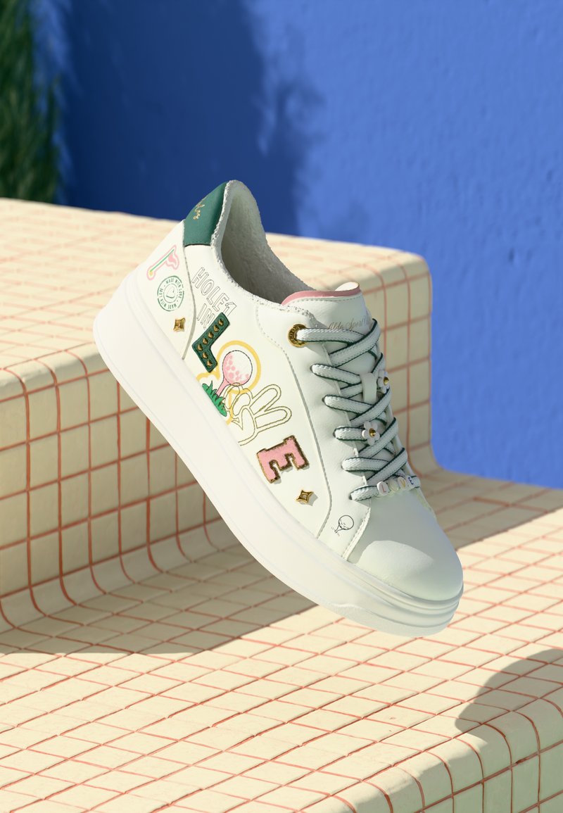 Sneaker bianco con design colorati a tema golf e "LOVE" sul lato, con piastra verde sul tallone e perline "LOVE" sui lacci, posizionata su una superficie piastrellata.