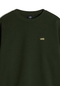 Sudadera verde oscuro hecha de tela suave. Presenta un cuello redondo y un pequeño logo amarillo de "VANS" en el pecho. Diseño sencillo, sin patrones.