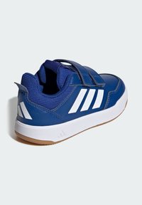 Niebieskie buty sportowe z syntetyczną cholewką, paskiem na rzep, białymi paskami ozdobnymi oraz gumową podeszwą z teksturowanym elementem żelowym.