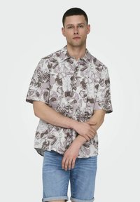 Kurzärmliges Blumenhemd in Helllila und Weiß, mit einer durchgehenden Knopfleiste, lockerer Passform und einem strukturierten, gemusterten Stoff.