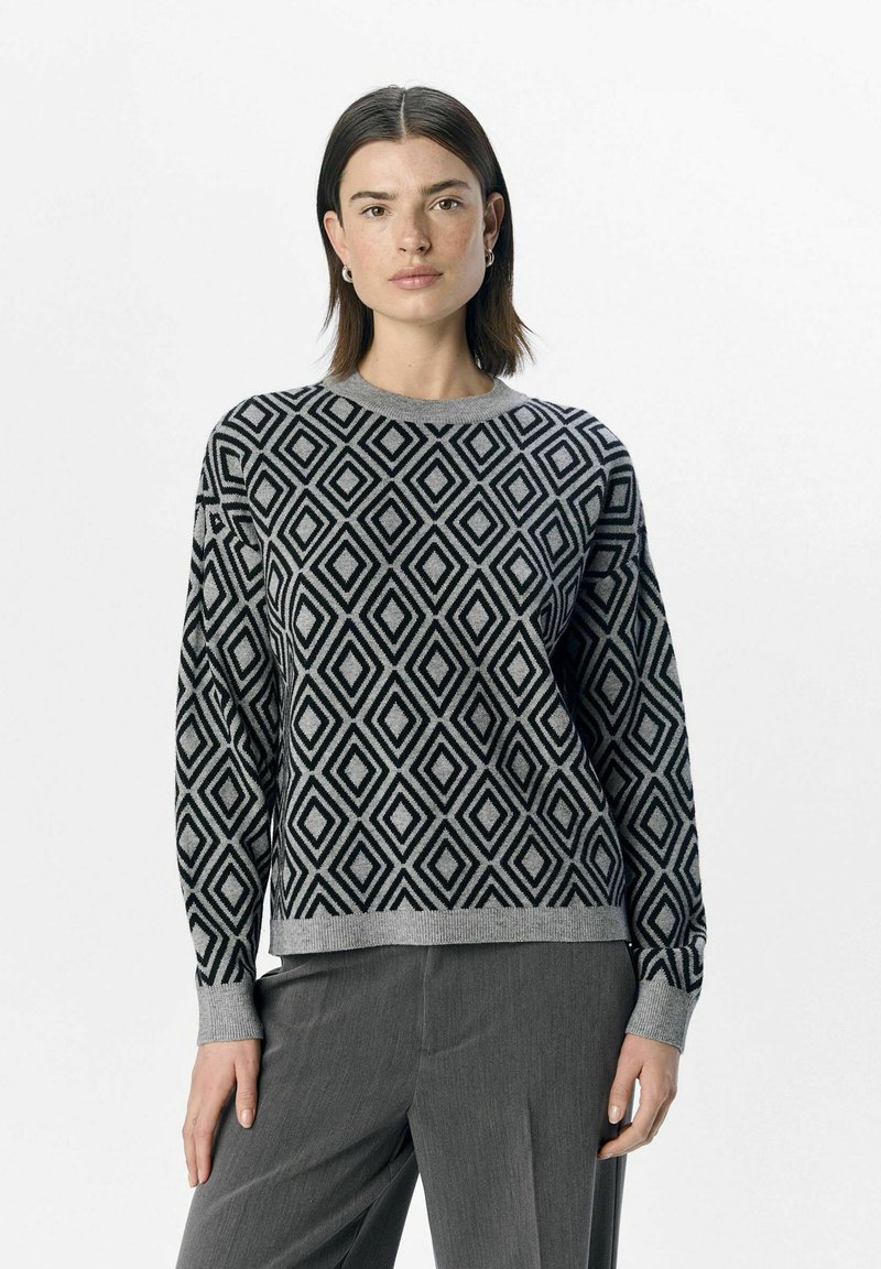 Schwarzer und grauer strickpullover mit Rautenmuster, langen Ärmeln und rundem Ausschnitt, kombiniert mit grauen Hosen.