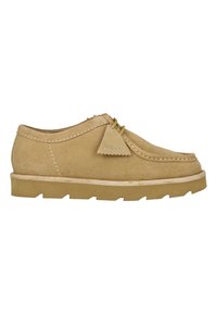 Lys brun semsket uformell sko med mokasinsøm, lisser og krepssåle, merket "Wallabees" og "Clarks Originals".