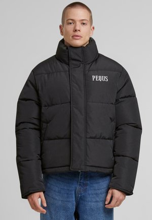 Black puffer jacket with a high collar, featuring horizontal quilted sections and white "PEQUS" logo on the left chest. Soft texture.