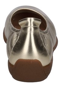 Chaussure plate en métal or avec bout rond et détail de talon découpé, présentant une texture lisse et une semelle en caoutchouc marron.