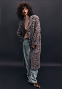 Leopardenmuster langer Mantel, beiger Rollkragenpullover, hellblaue Jeans und spitze Leopardenmuster High Heels. Besitzt strukturierte Textur und durchdachtes Design.