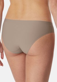 Beige seamless underwear with a smooth, stretchy texture. The design features a low-rise cut, providing moderate coverage at the back.