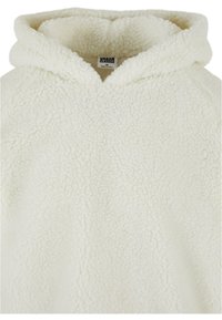 White fleece hoodie with a textured, fluffy exterior. Features a spacious hood and a tag labeled “URBAN CLASSICS” on the inside.